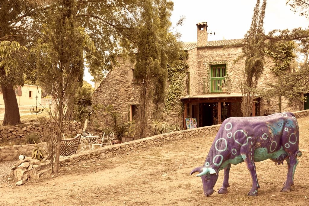 Stone house with a psychedelic cow sculpture in the courtyard
