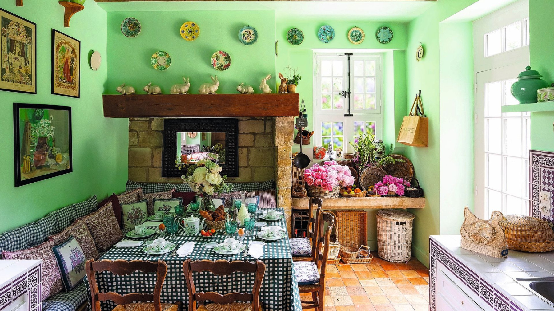 A country dining room in green with a fireplace and baskets of flowers