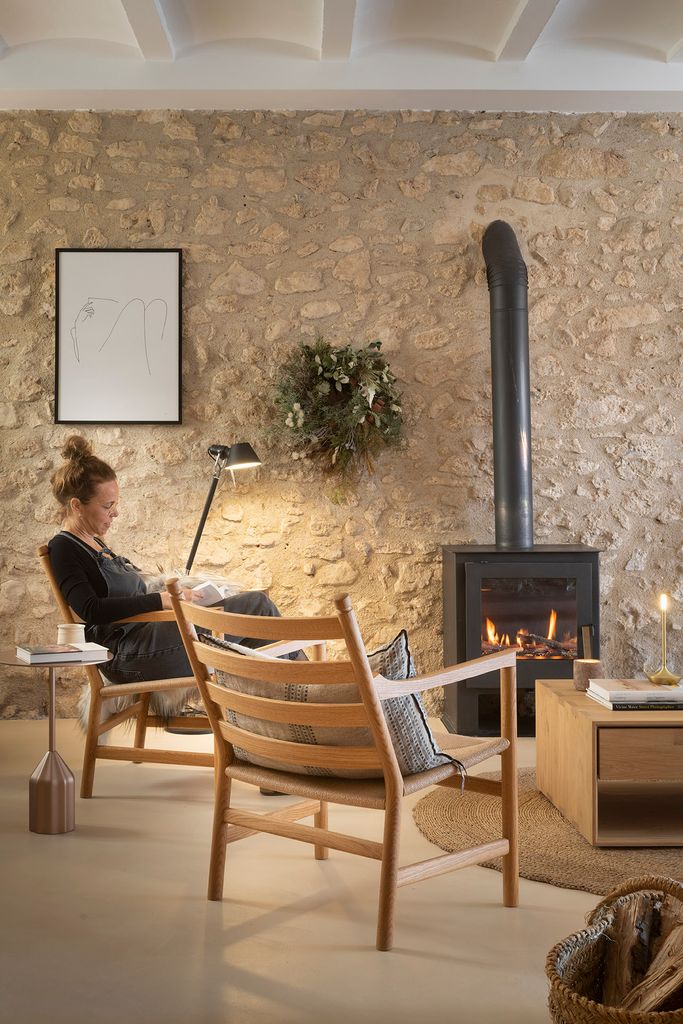 A reading corner beside a wood stove and a stone wall in the medieval house