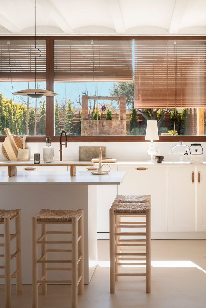 White kitchen with an island and handmade chairs in Susana Cots' home