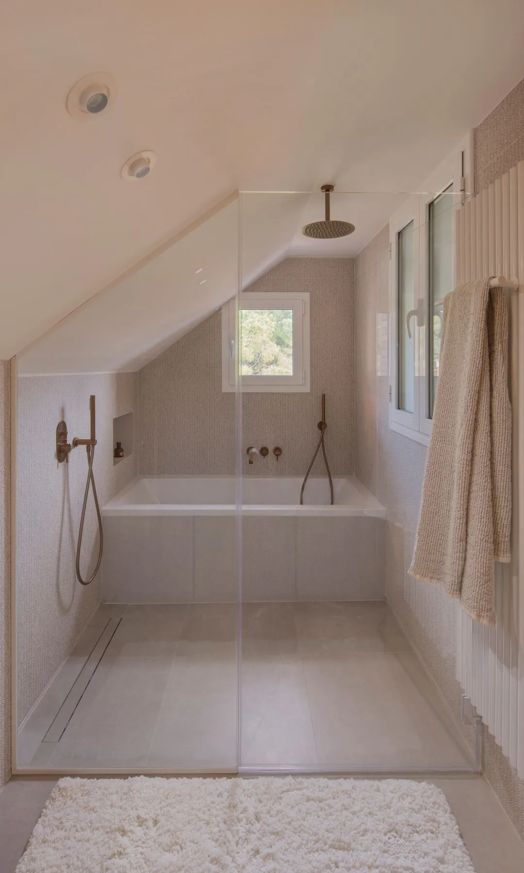 Badewanne und Dusche hinter Glaswänden unter der Dachschräge